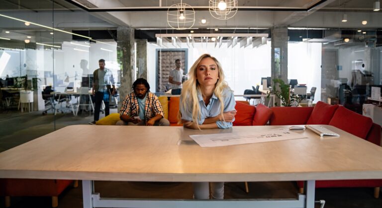 Portrait of unhappy tired young business woman working in office background